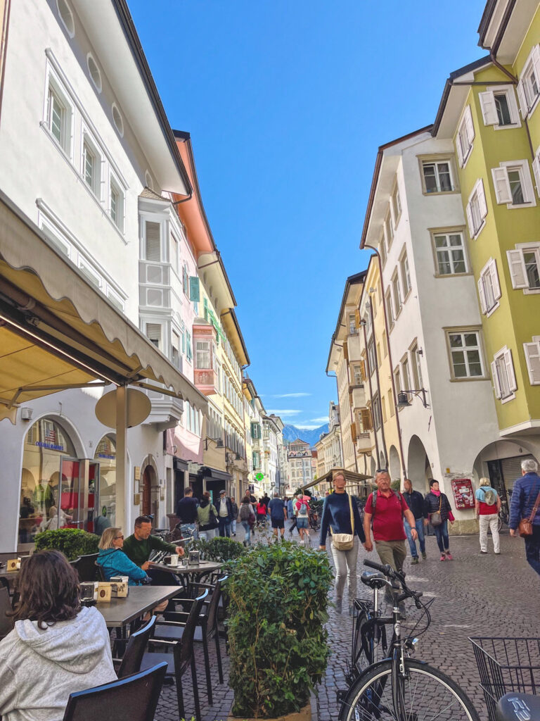 Elegant arcaded street in Bolzano’s old town with painted facades, bicycles, and boutique shops, capturing the city’s blend of Italian and Austrian charm.
